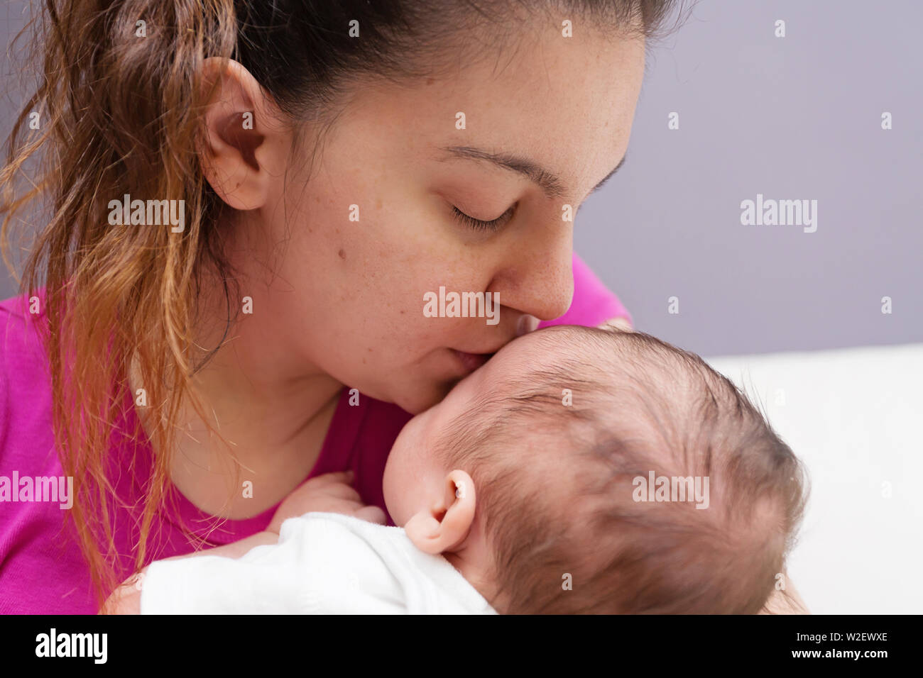 Amorevole snuggling Mom e baciare il suo nuovo di zecca baby Foto Stock