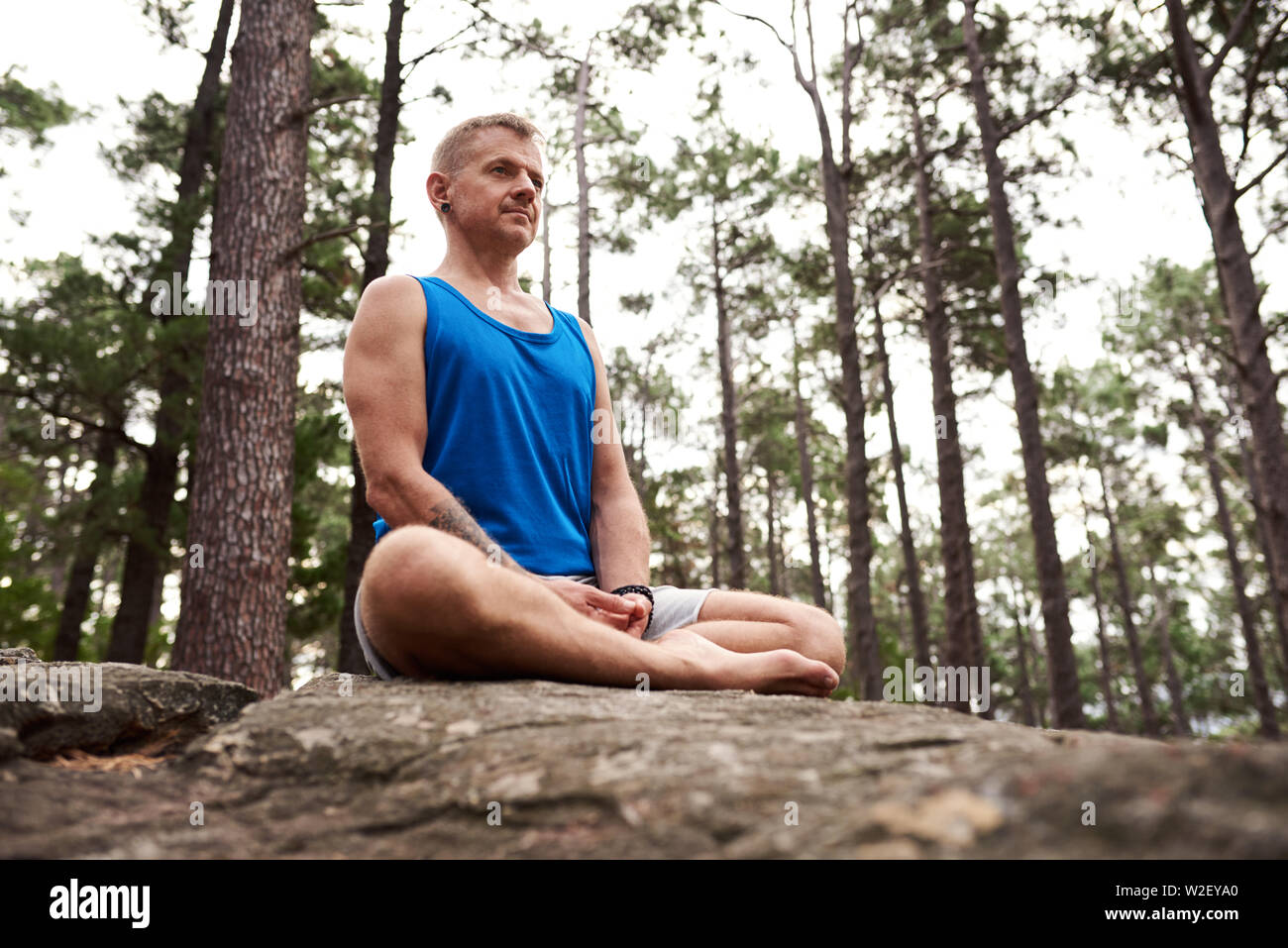 L'uomo meditando seduto su una roccia nella foresta Foto Stock