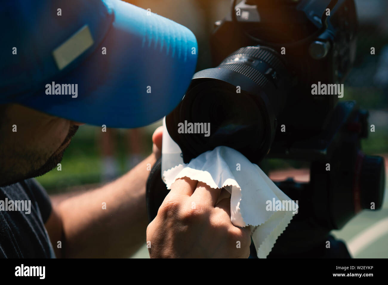 Tagliate le mani dell uomo di pulizia della lente della fotocamera. Installazione all'aperto. Foto Stock