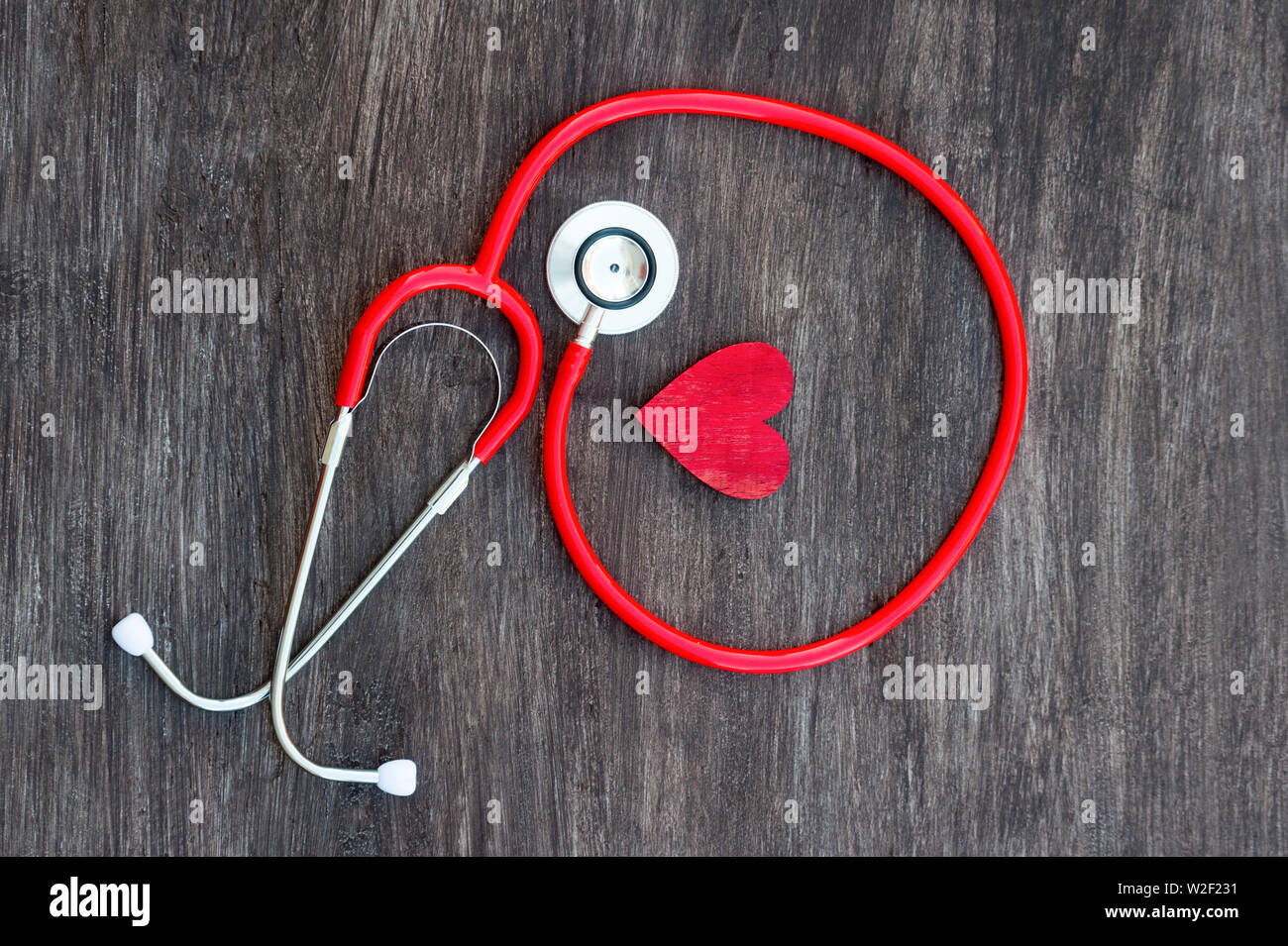 Lo stetoscopio e il cuore rosso su sfondo di legno. Health care concept Foto Stock
