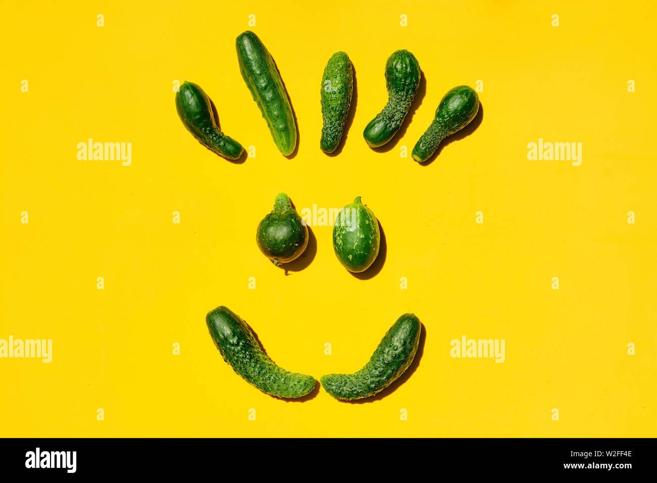 Diverse dimensioni e forme cetrioli su uno sfondo giallo forma una faccia sorridente. Smile, viso, gli Emoji, sorridente faccina felice, felice gli Emoji, sorridente gli Emoji. Foto Stock