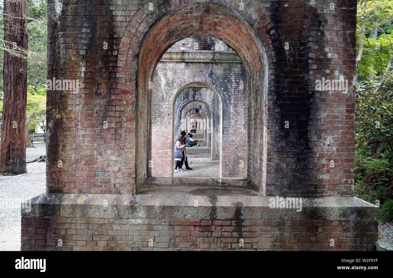 Giapponese coppie youg rilassante sotto Suirokaku mattone acquedotto, tempio di Nanzenji, Kyoto, Giappone Foto Stock