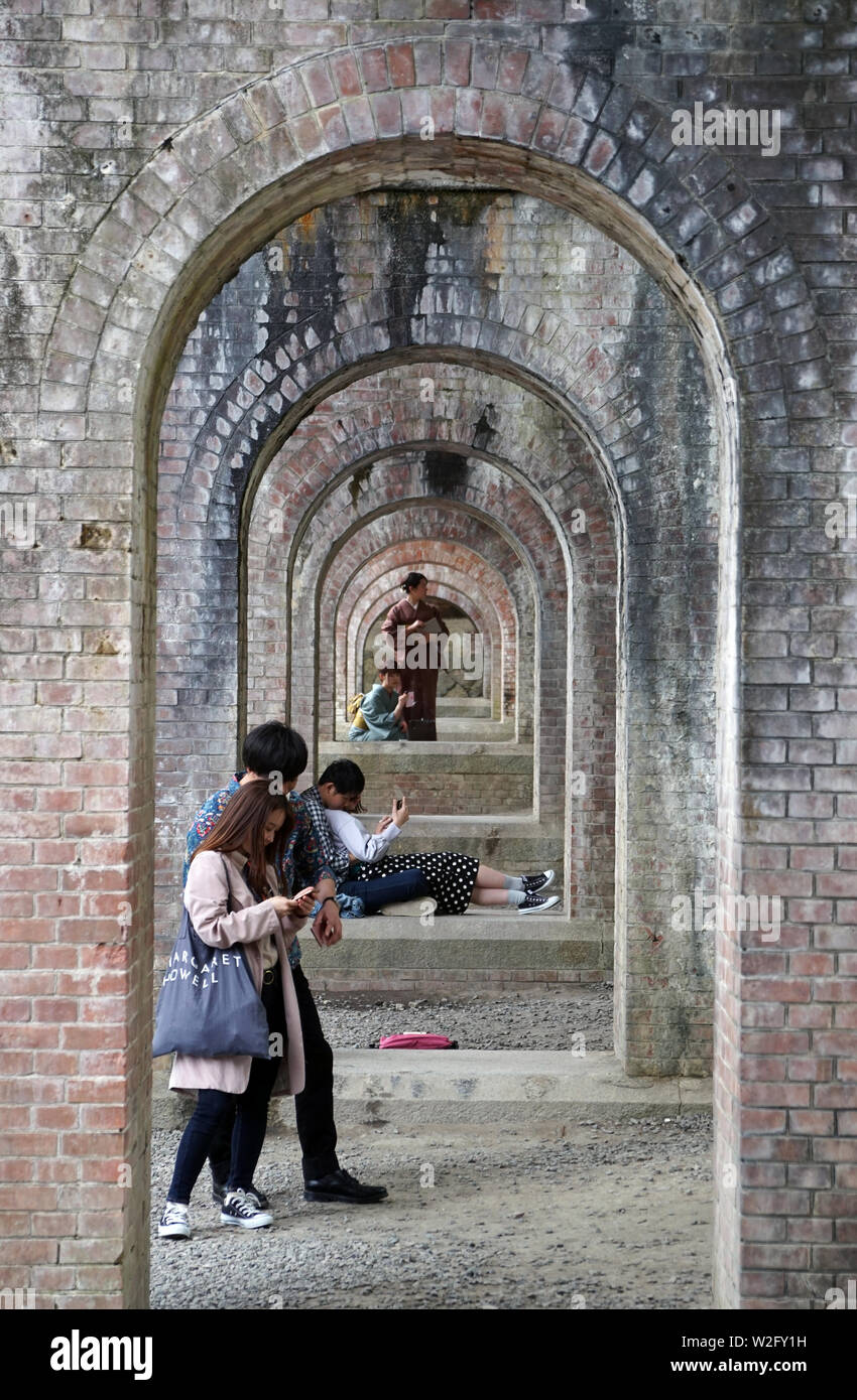 Giapponese coppie youg rilassante sotto Suirokaku mattone acquedotto, tempio di Nanzenji, Kyoto, Giappone Foto Stock