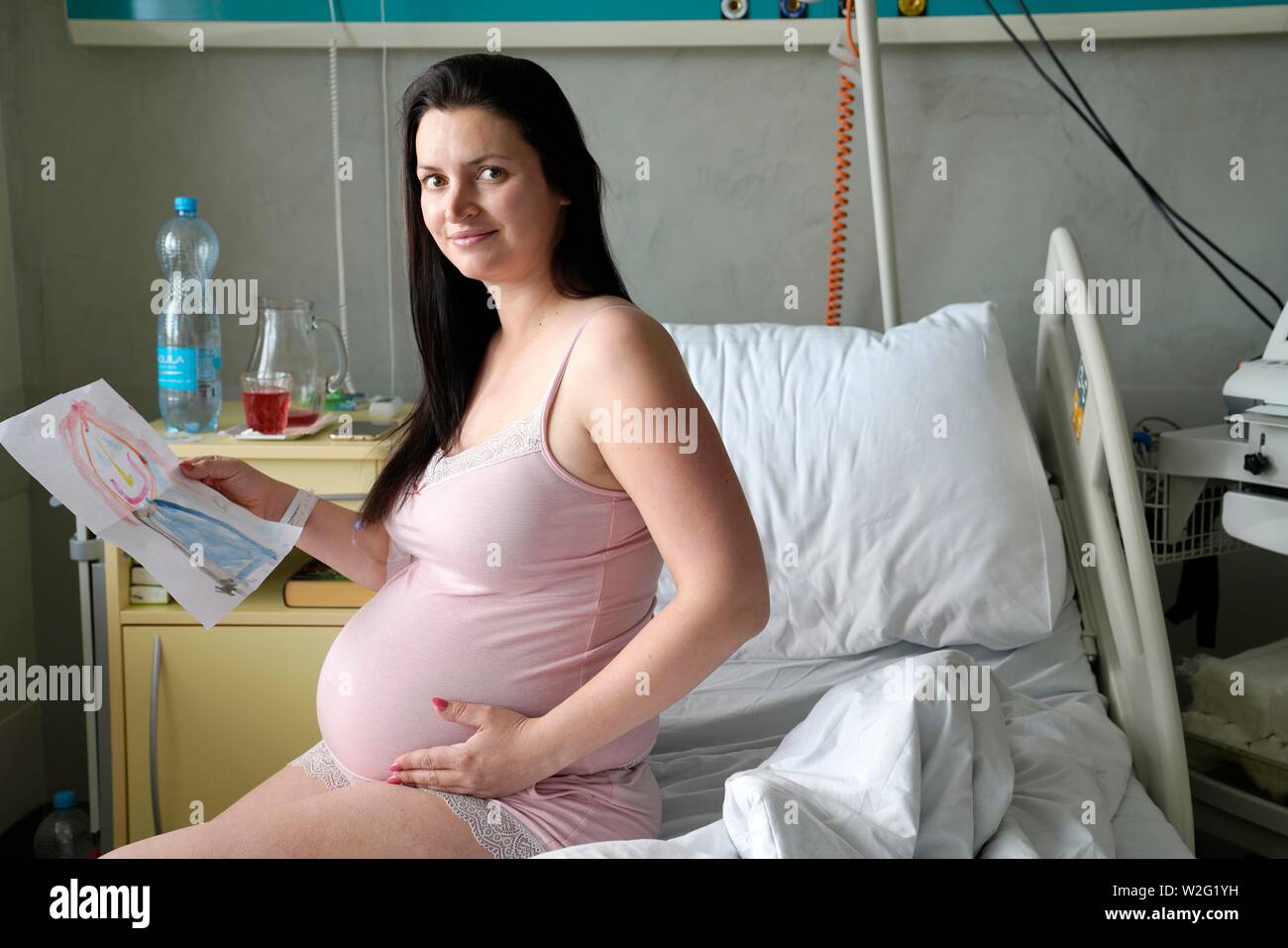 Donna incinta seduta su sickbed in sickroom, ad alto rischio di gravidanza, Karlovy Vary, Repubblica Ceca Foto Stock