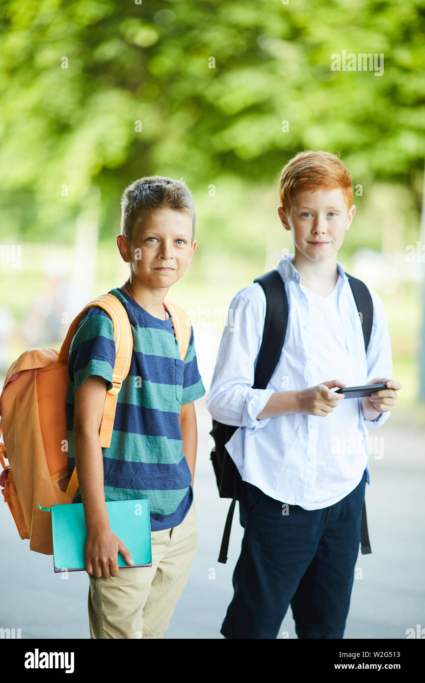 Scuola di due migliori amici che posano per una foto per i loro genitori il loro primo giorno di lezioni a scuola nuova Foto Stock