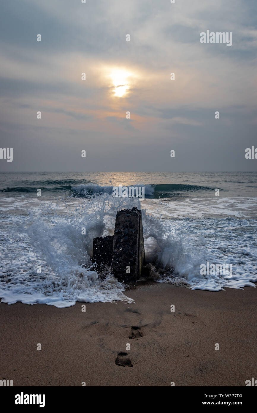 Tramonto su roccia e impronte di amanti della natura nella spiaggia di sabbia di pondicheery india. Foto Stock