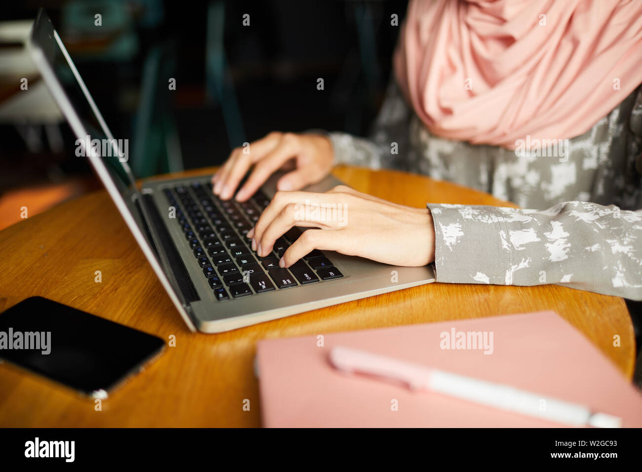 Mani femminili di studente di college in hijab lavorando sul computer portatile presso il cafe tabella Foto Stock