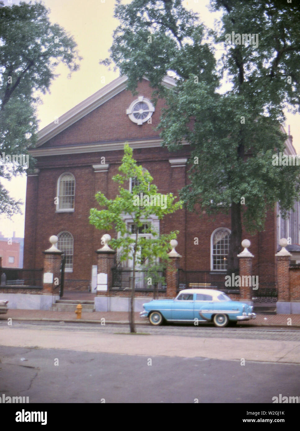 Macchina parcheggiata in strada di fronte a quello che sembra essere un vecchio edificio della chiesa ca. 1961 Foto Stock