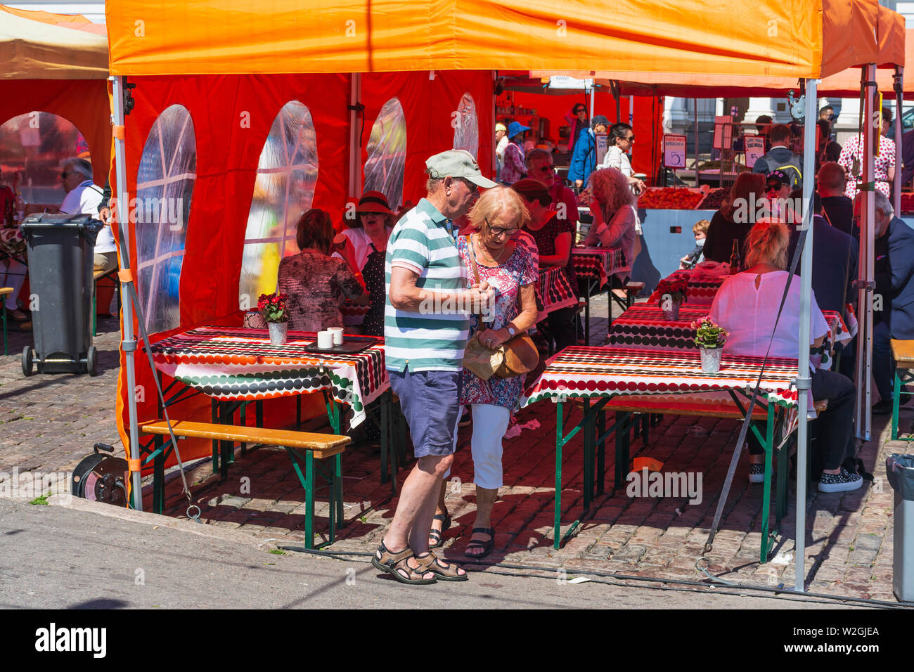 I turisti in una tenda arancione che hanno uno spuntino nella piazza del mercato di Helsinki Foto Stock