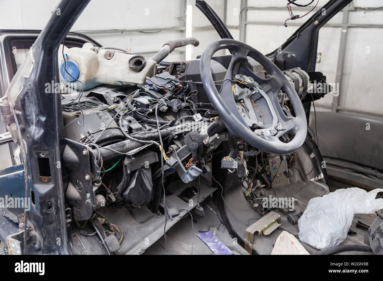 Per interni auto nel retro di un furgone con un cruscotto smontato e vista sul volante durante la preparazione di un veicolo officina di riparazione. Auto servi Foto Stock