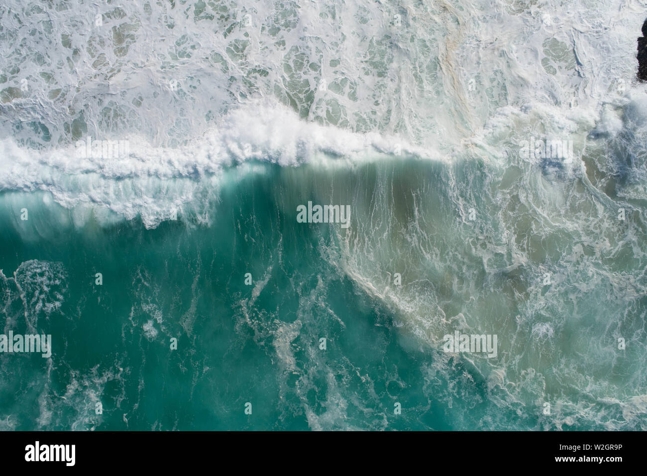 Vista aerea di una delle onde che si infrangono sulla battigia e rotolamento nell'oceano. Tempesta alla ricerca di foto di un mare oceano e acqua blu con motivi di sabbia Foto Stock