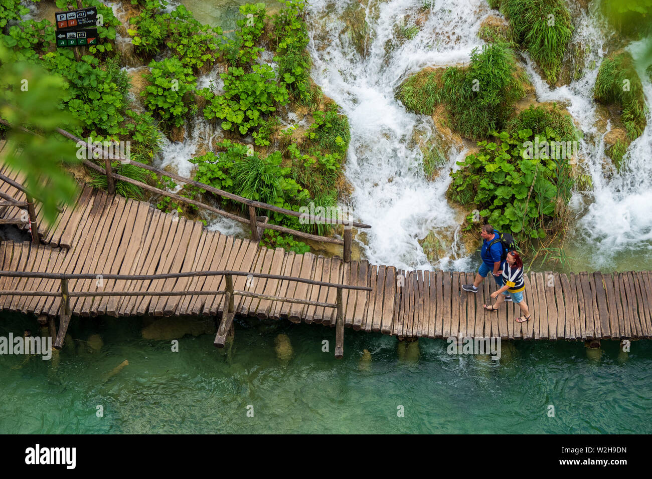 Gli escursionisti passando le cascate di acqua correre verso il basso nel colore turchese Lago Kaluđerovac presso il Parco Nazionale dei Laghi di Plitvice in Croazia Foto Stock