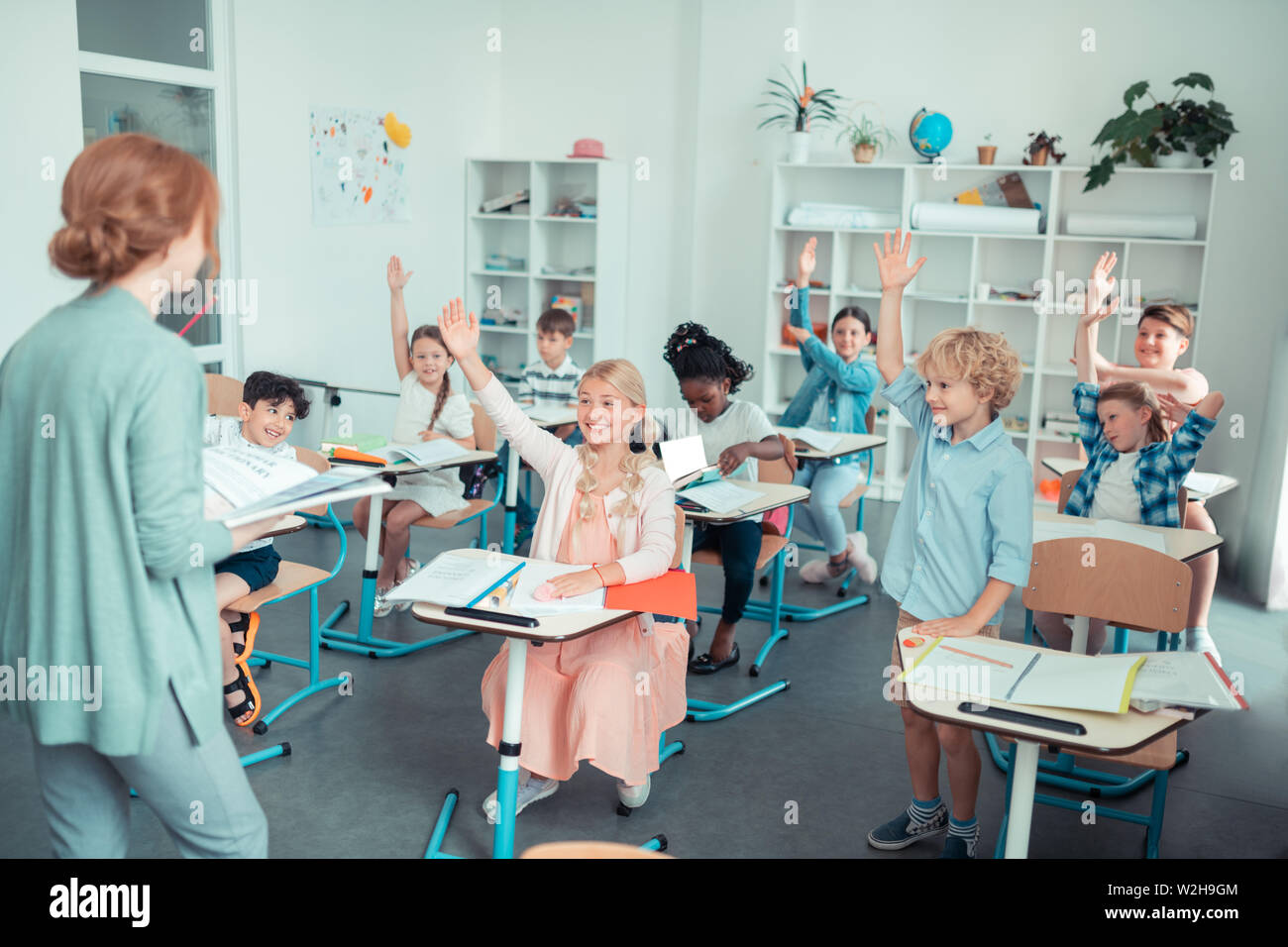 Bambini sorridenti in aula interagendo con l'insegnante. Foto Stock