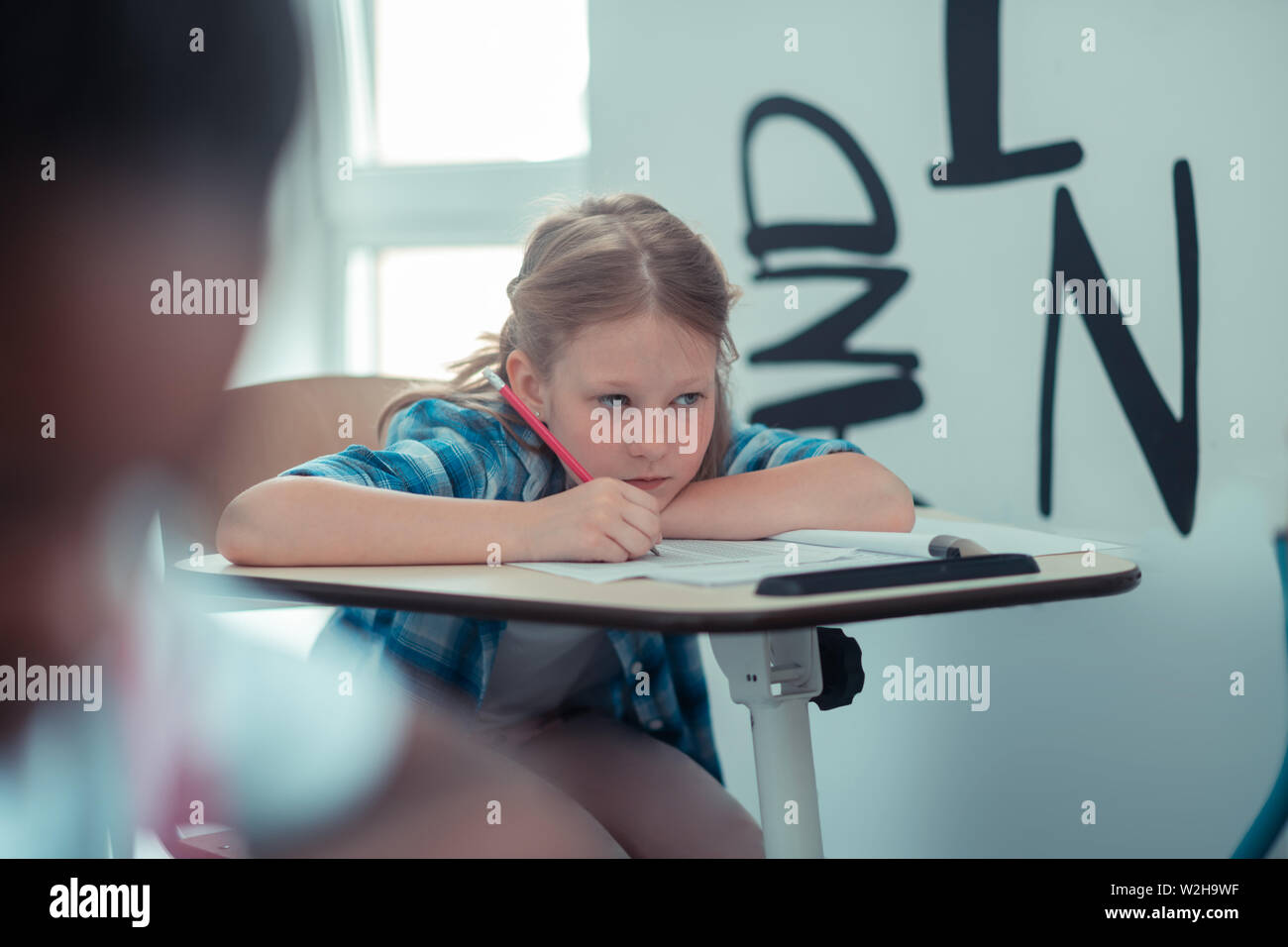 Riflessivo schoolgirl tring per ricordare una regola frome il libro. Foto Stock