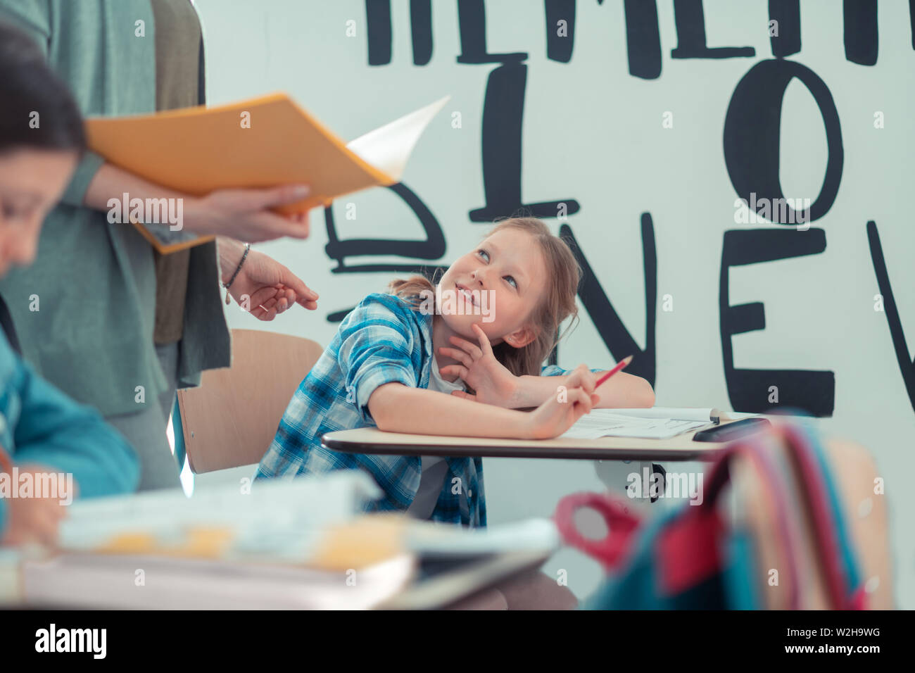 Schoolgirl chiedendo il suo insegnante di darle un cue. Foto Stock