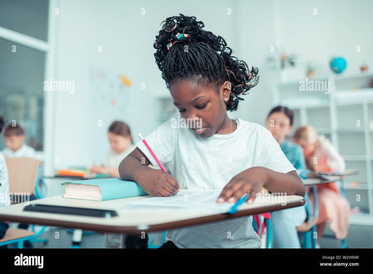 La scolaretta facendo somme con concentrati di fronte al test . Foto Stock