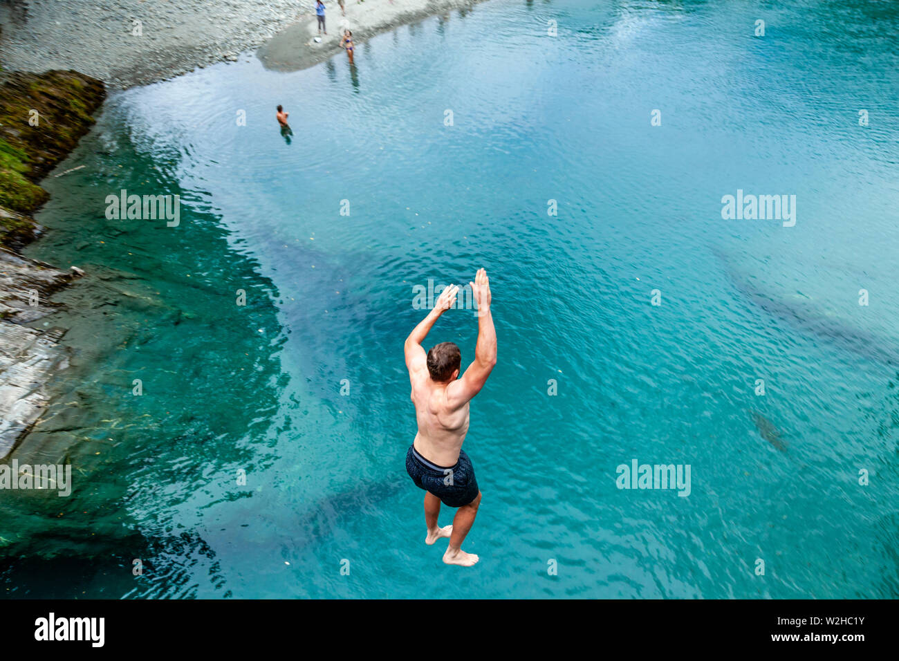 Un giovane uomo salti in pool di blu (vicino Makarora), Mt Aspiring National Park, Isola del Sud, Nuova Zelanda Foto Stock