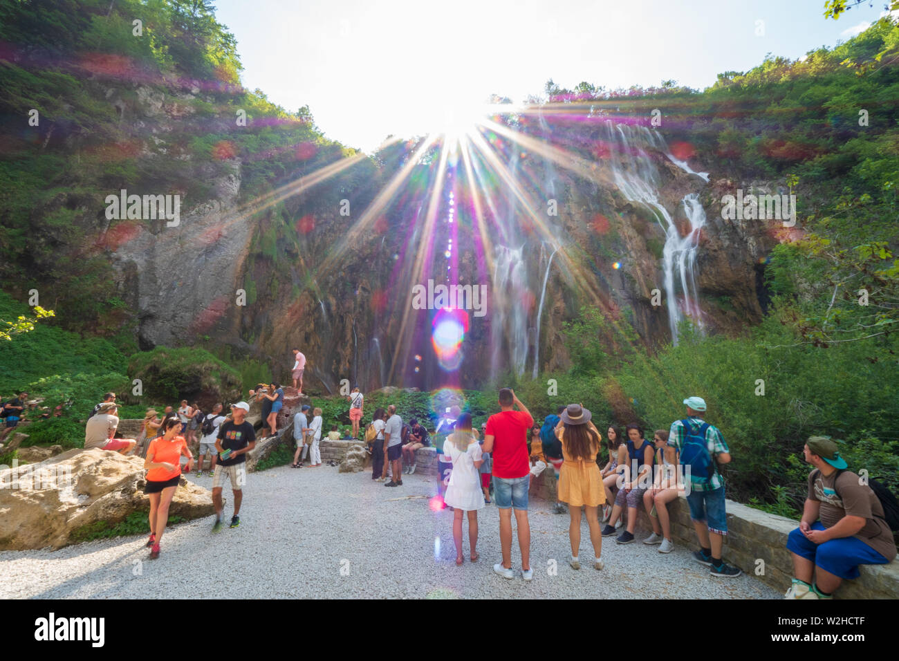 La folla di persone in piedi di fronte alla grande cascata, il Veliki Slap, presso il Parco Nazionale dei Laghi di Plitvice in Croazia Foto Stock