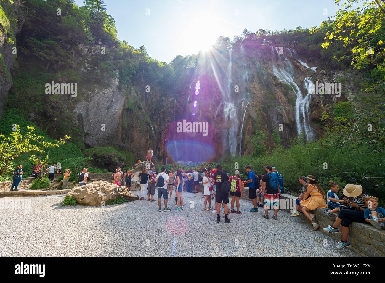 La folla di persone in piedi di fronte alla grande cascata, il Veliki Slap, presso il Parco Nazionale dei Laghi di Plitvice in Croazia Foto Stock