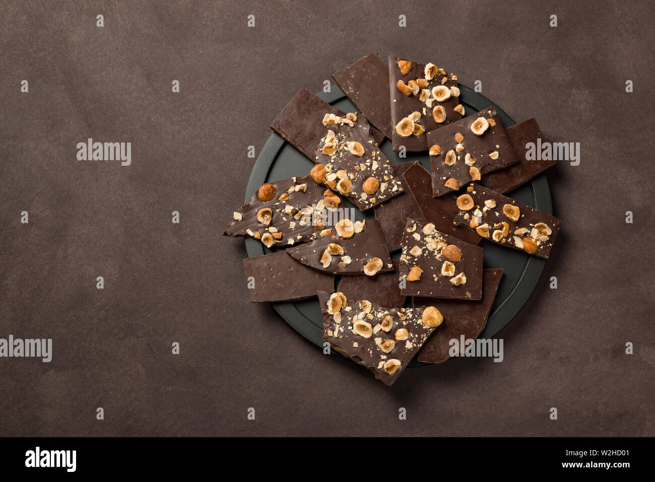 Nocciola scuro pezzi di cioccolato sulla piastra nera Foto Stock Nocciola scuro pezzi di cioccolato sulla piastra nera Foto Stock