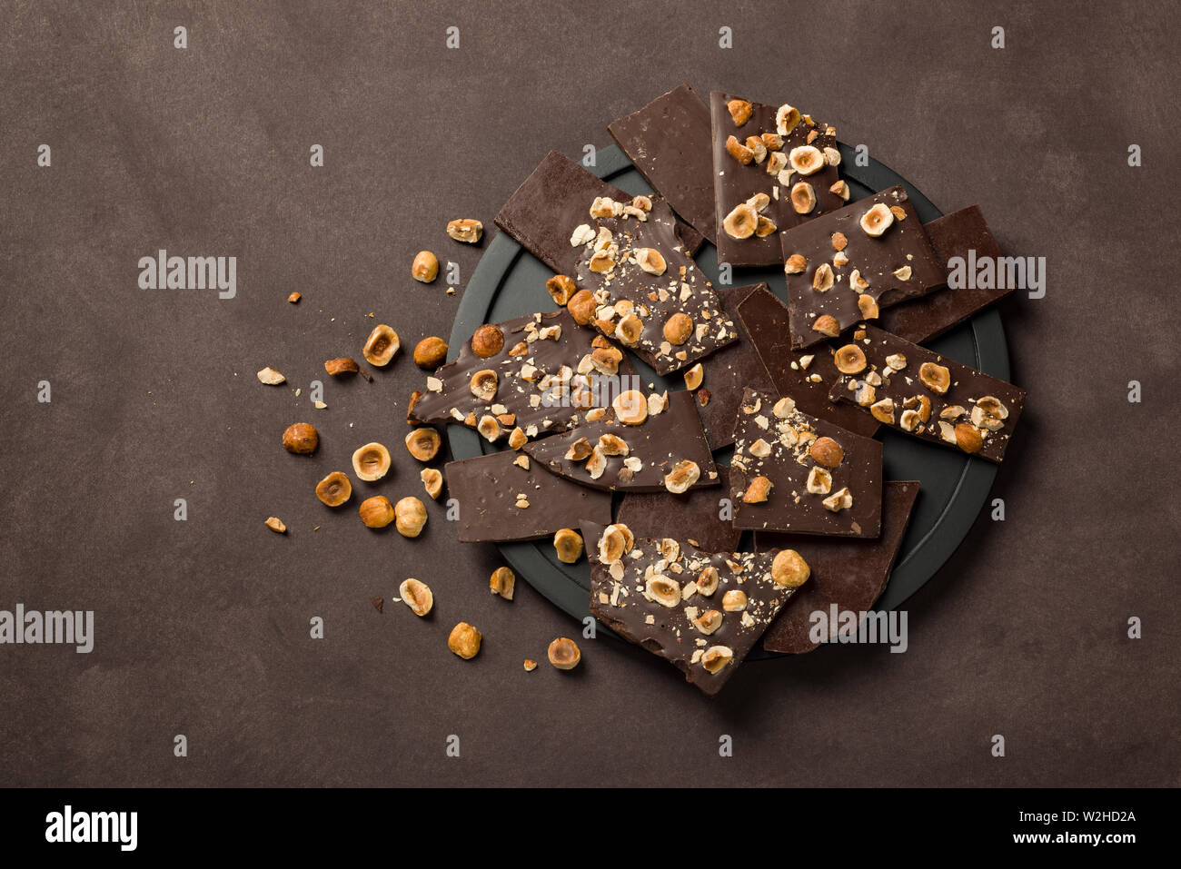 Nocciola scuro pezzi di cioccolato sulla piastra nera Foto Stock Nocciola scuro pezzi di cioccolato sulla piastra nera Foto Stock