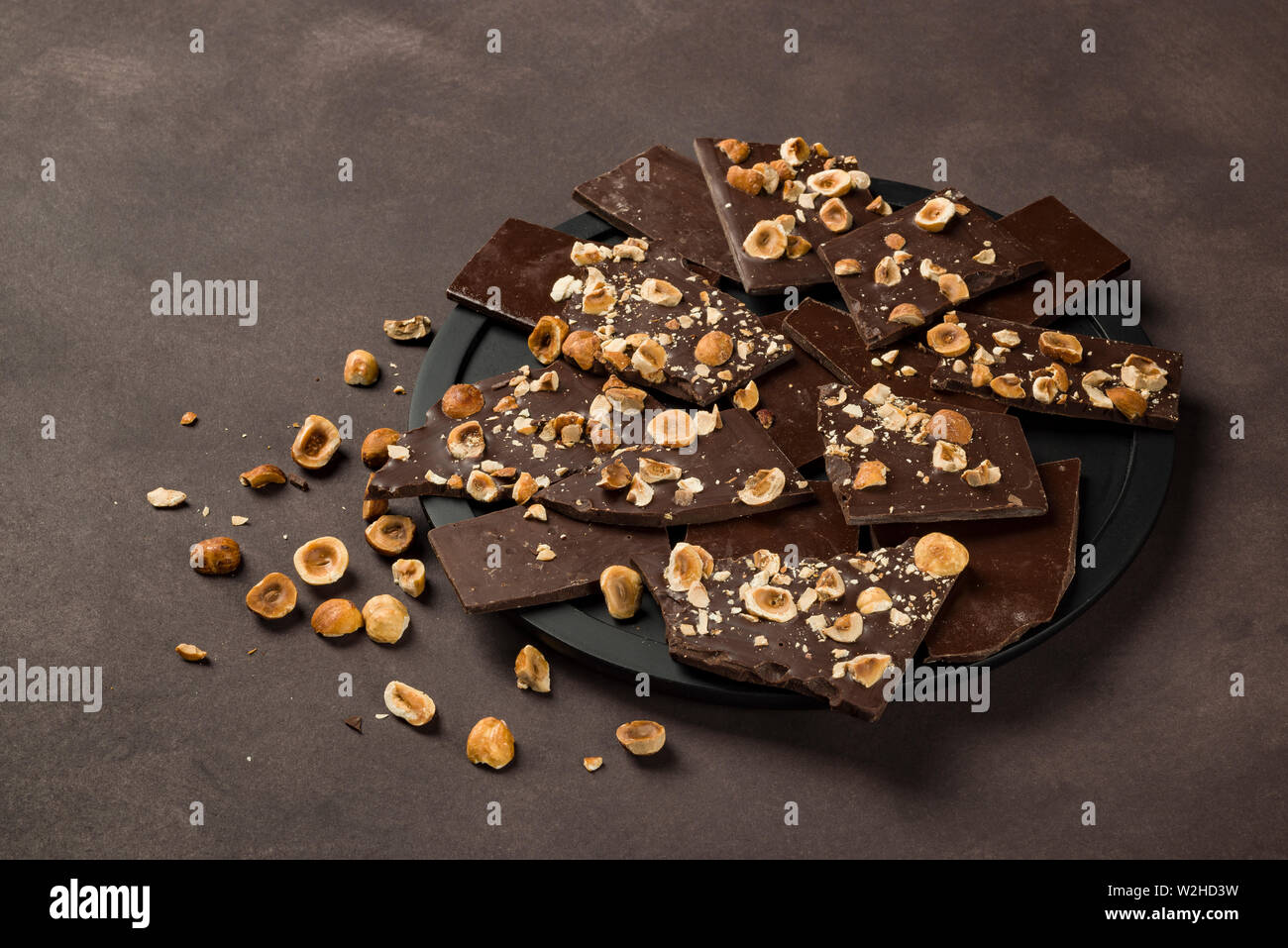 Nocciola scuro pezzi di cioccolato sulla piastra nera Foto Stock Nocciola scuro pezzi di cioccolato sulla piastra nera Foto Stock