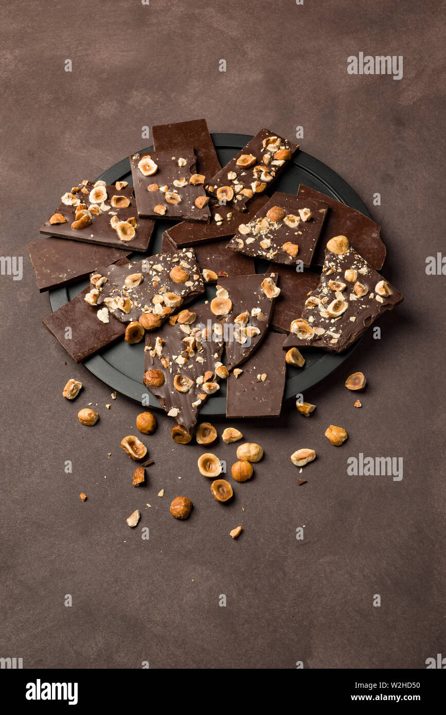 Nocciola scuro pezzi di cioccolato sulla piastra nera Foto Stock Nocciola scuro pezzi di cioccolato sulla piastra nera Foto Stock