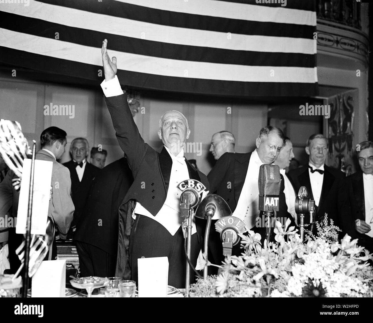 Uomo in smoking in piedi di fronte a CBS radio microfono, mano alzata ca. 1936 Foto Stock