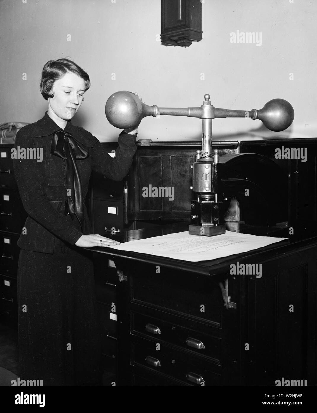 Donna dispositivo dimostrando che impressiona il grande sigillo degli Stati Uniti su alcuni documenti ufficiali ca. 1935 Foto Stock