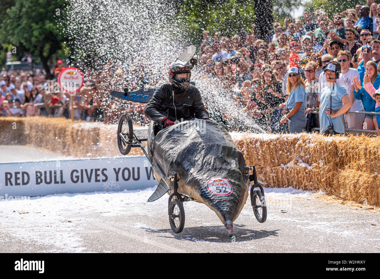 Driver dei delfini a competere in Red Bull Soapbox Race 2019 a Alexandra Park, London, Regno Unito. Saltando su rampa con persone Foto Stock