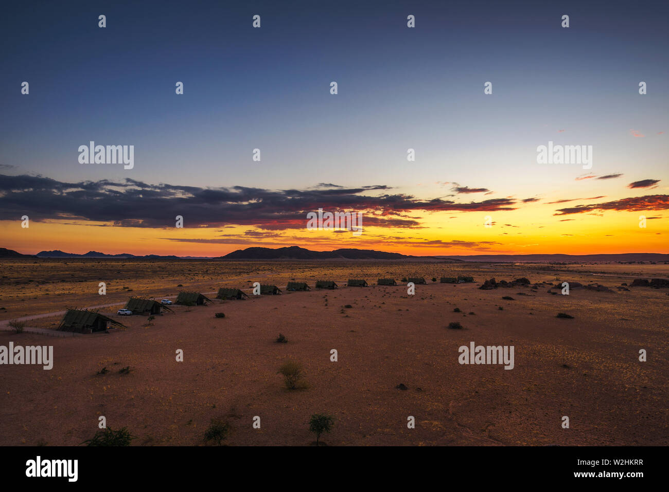 Il tramonto sopra i piccoli chalets di una desert lodge vicino al Sossusvlei in Namibia Foto Stock