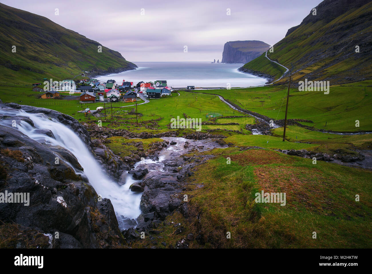 La cascata e il villaggio di Tjornuvik nelle isole Faerøer Foto Stock