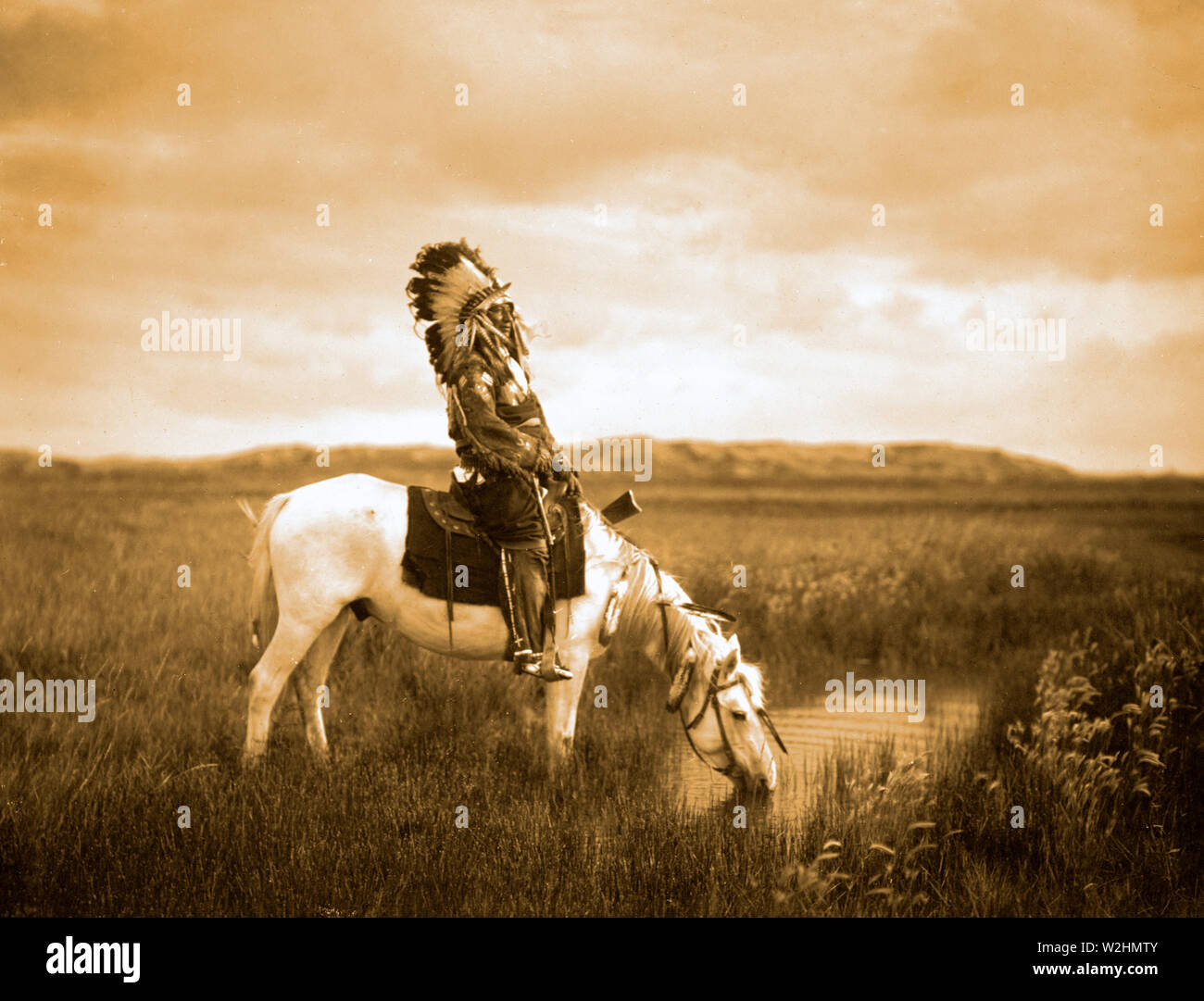 Edward S. Curtis nativi indiani americani - Rosso Hawk, un guerriero Oglala, seduto su un cavallo che è di bere da un piccolo stagno nel Badlands ca. 1905 Foto Stock