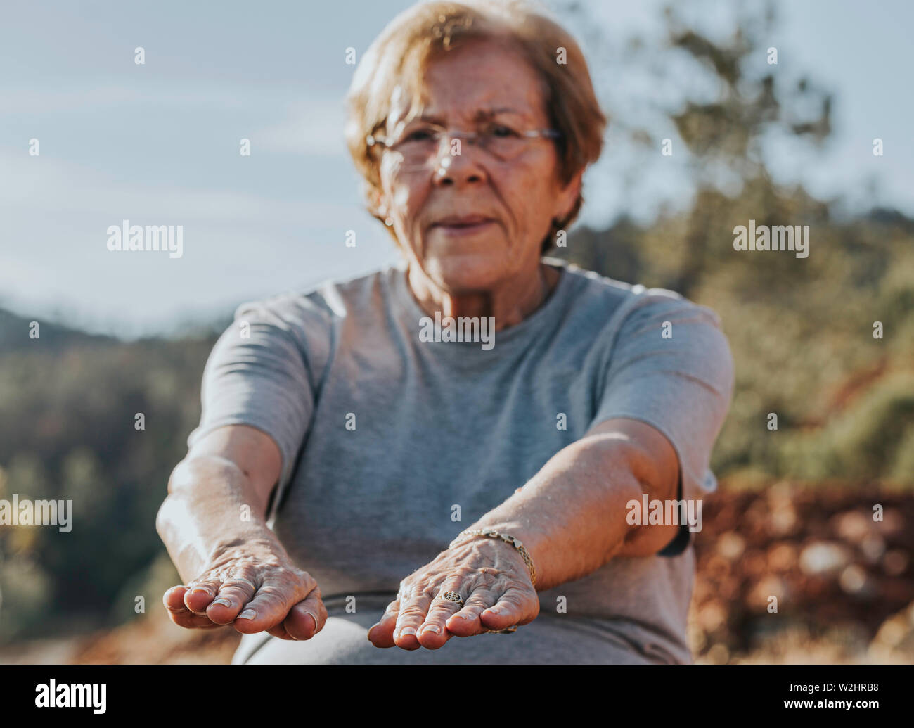 Donna anziana facendo loro si estende nel parco con il fuoco selettivo nelle dita Foto Stock