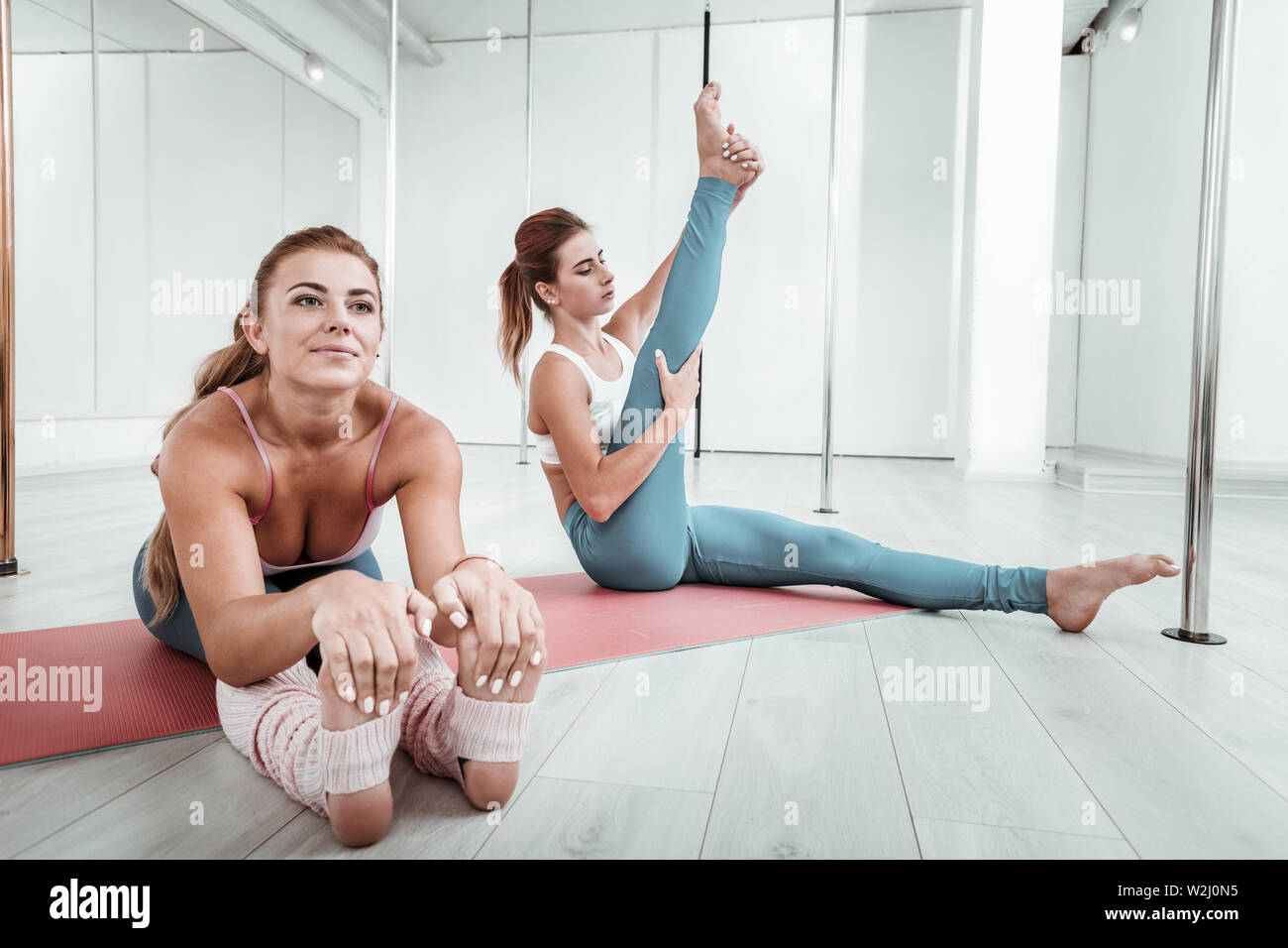 Due sportivi facendo esercizi di stretching seduta sul pavimento. Foto Stock