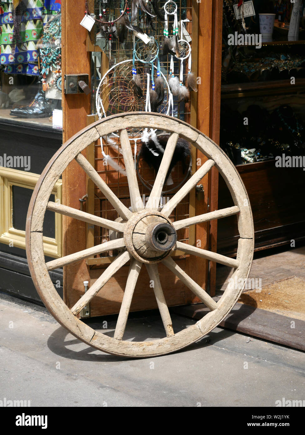 Legno ruota di carro al di fuori del negozio di vendita di mercanzia indiana in Portobello Road, London, Regno Unito Foto Stock