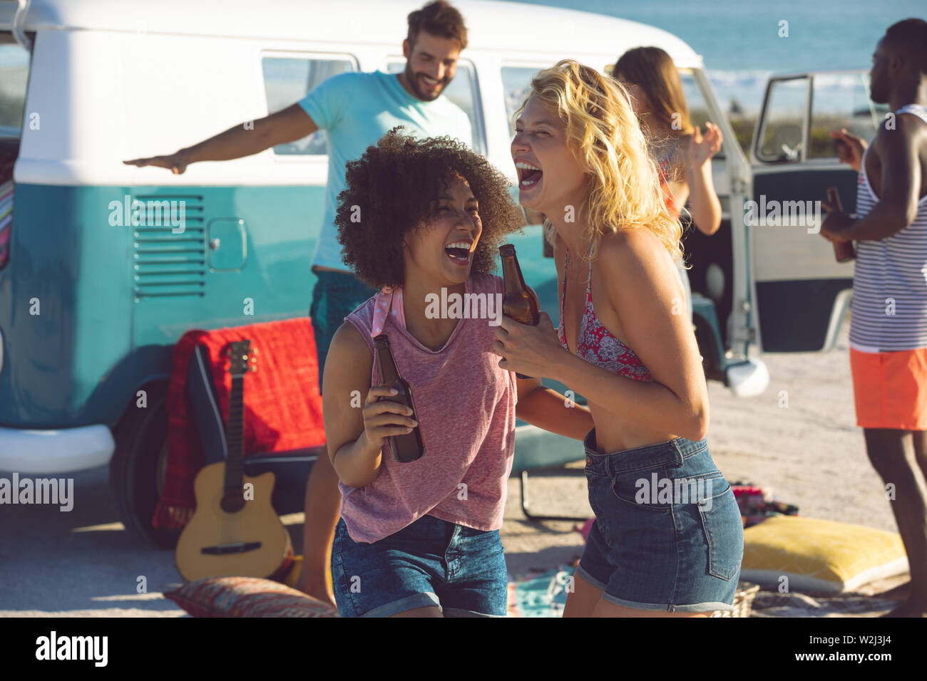 Gruppo di amici divertendosi vicino a camper van a beach Foto Stock