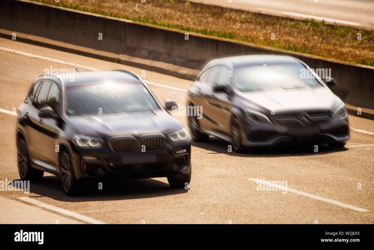 Un veicolo ogni dalla BMW e Mercedes-Benz guida ad alta velocità una accanto all'altra su una superstrada Foto Stock