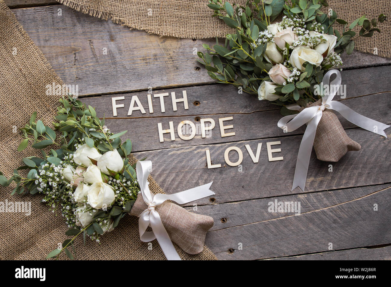 Sfondo rustico con mazzi e tela con le parole di fede, di speranza e di amore enunciato nelle lettere di legno Foto Stock