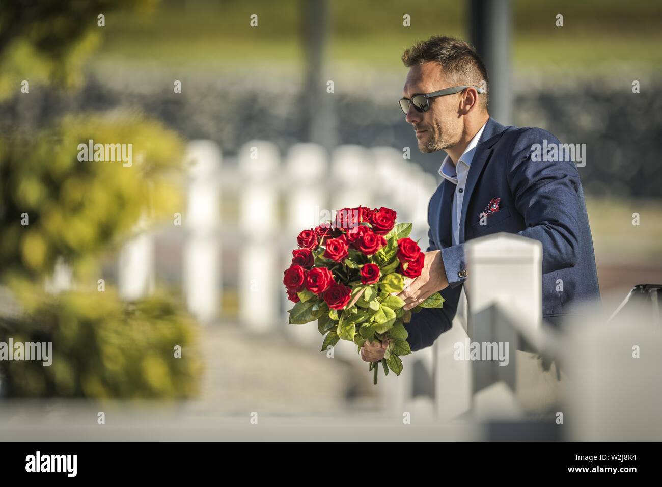 Attraenti uomini caucasici nella sua 30s con bouquet di fiori. Mantenendo il mazzo di rose rosse e attesa per la sua ragazza. Foto Stock