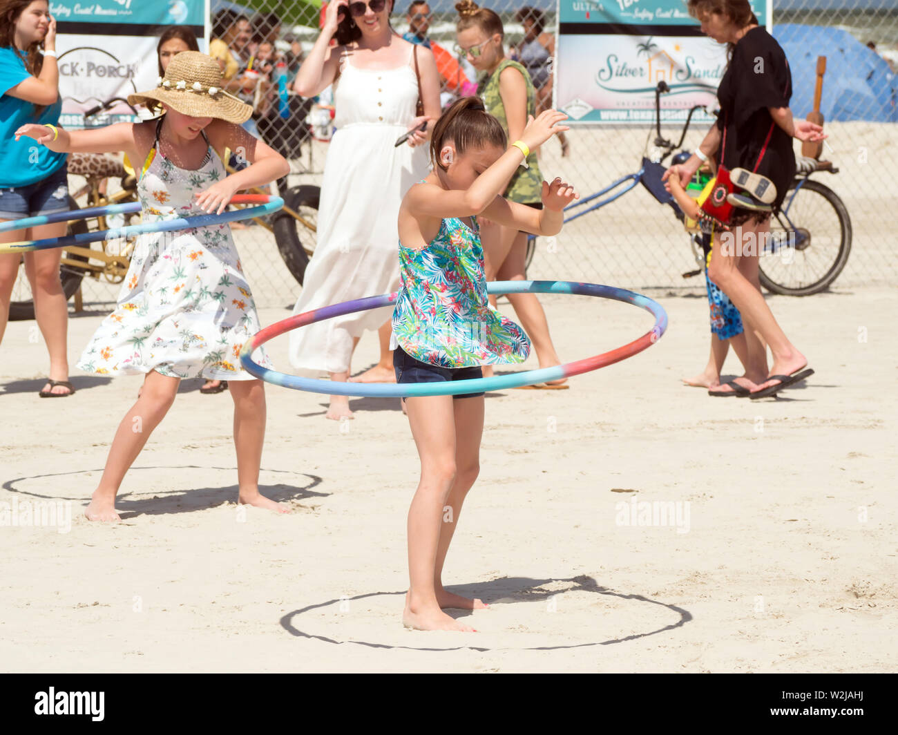 Le ragazze giovani pratica fa roteare Hula Hoops al 2019 Texas Sandfest in Port Aransas, Texas, Stati Uniti d'America. Foto Stock