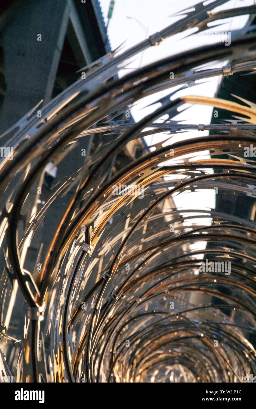 BLOCCO: Spirali di filo spinato lungo la cima di una recinzione in un complesso industriale sotto una strada sopraelevata a Perth Amboy, New Jersey. Foto Stock