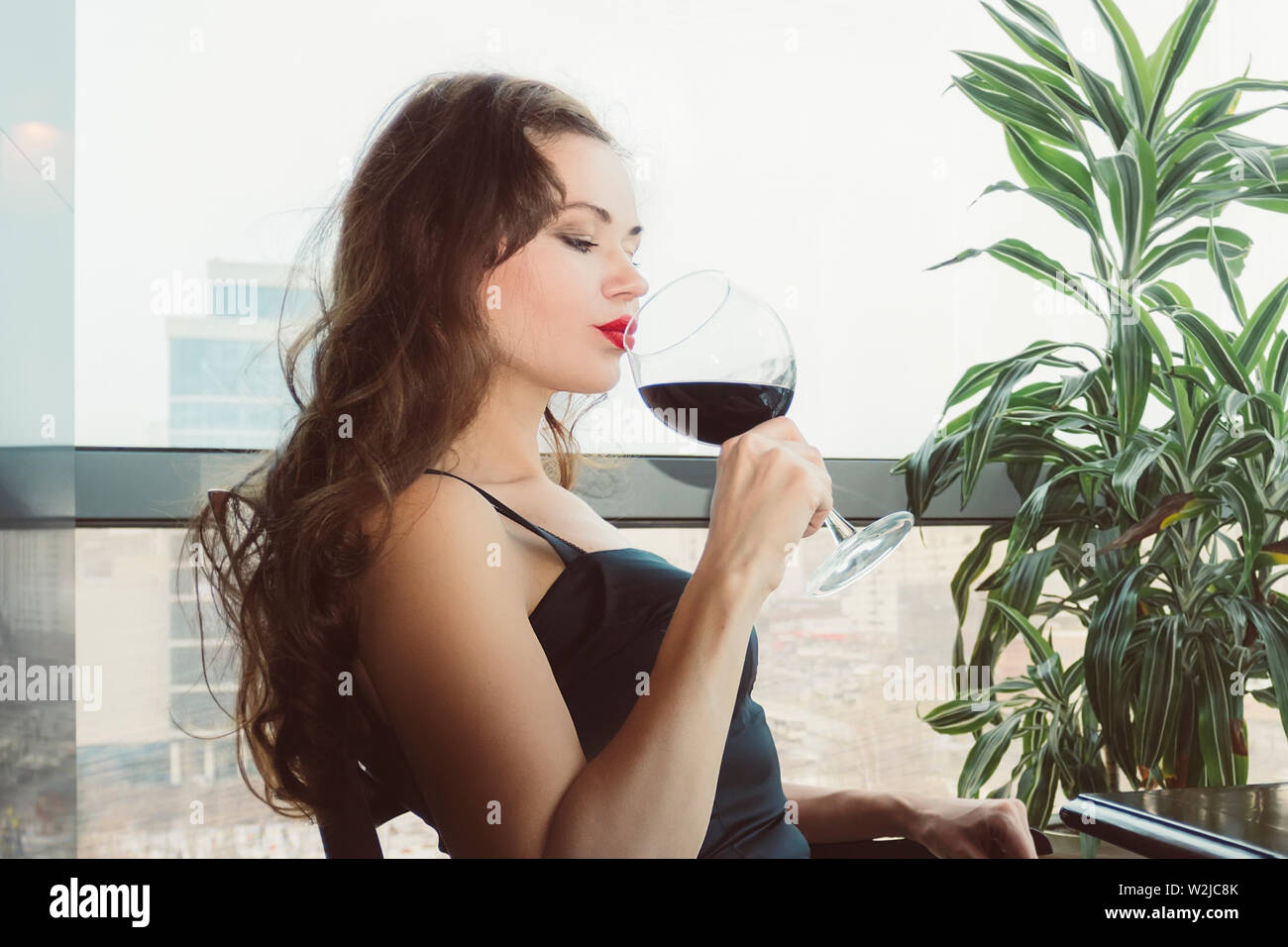 Closeup Ritratto di giovane donna cliente di bere il vino rosso con gli occhi chiusi. Donna di bere vino, prendendo un sorso di un bicchiere di vetro. Degustazione di vino a th Foto Stock
