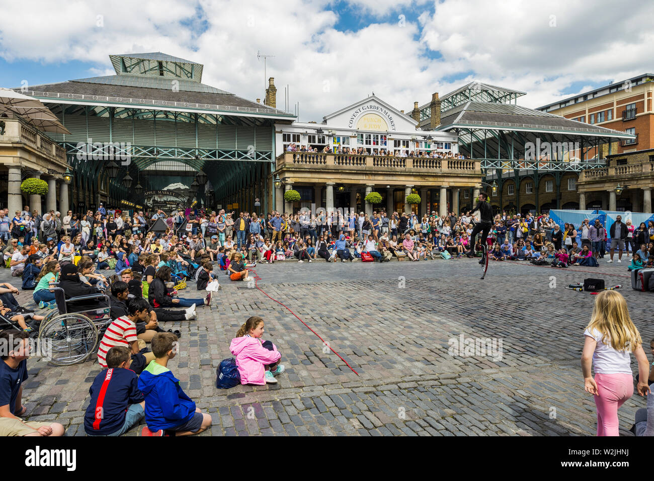 Un esecutore di strada intrattiene la folla di turisti al mercato di Covent Garden, Londra Foto Stock