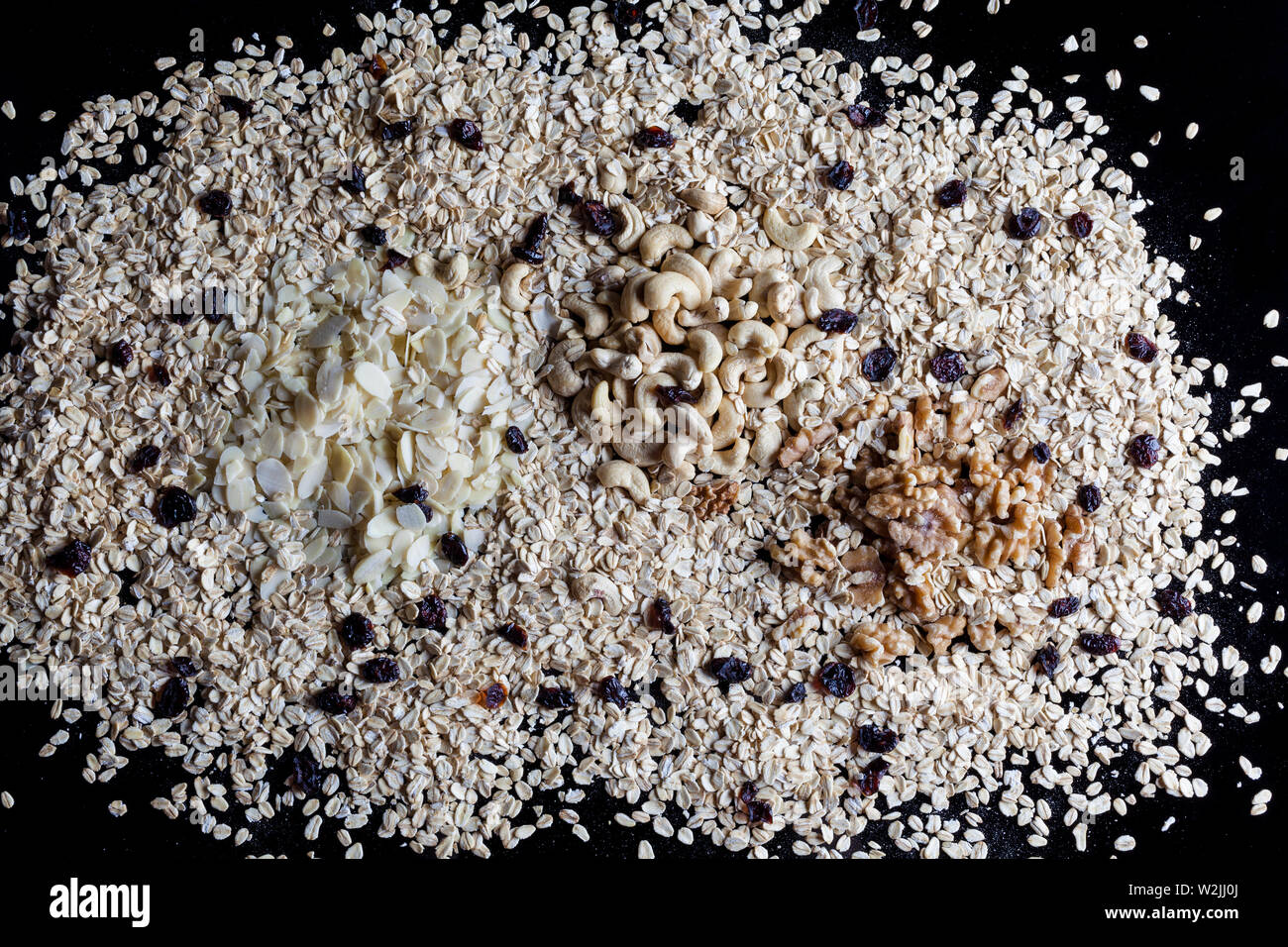 Granola INGREDIENTI Farina di avena fiocchi di mandorle sgusciate Noci e anacardi su sfondo nero direttamente sopra Foto Stock