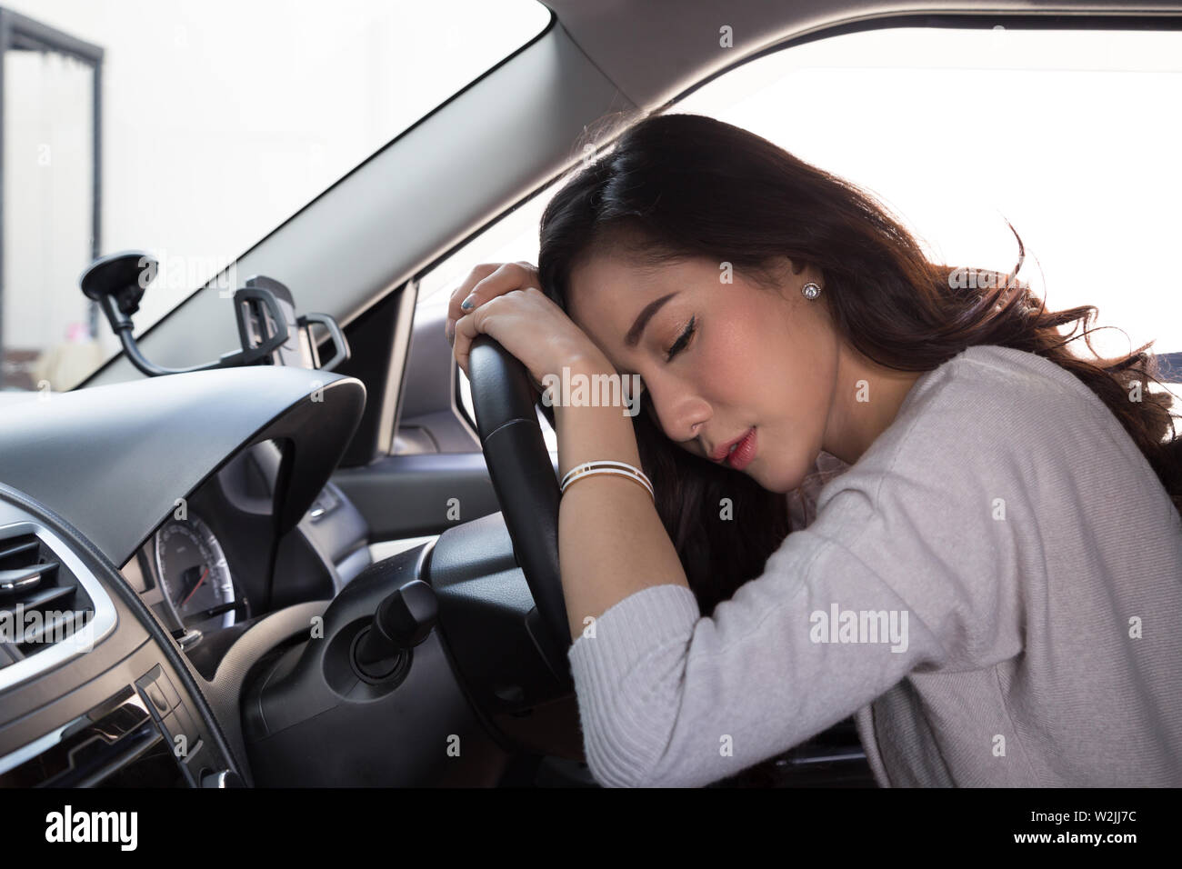 Stanco giovane donna dormire in auto, duro lavoro provoca una cattiva salute, Sit addormentato mentre la macchina è su una luce rossa, ingorghi di traffico o concetto oberato di lavoro Foto Stock