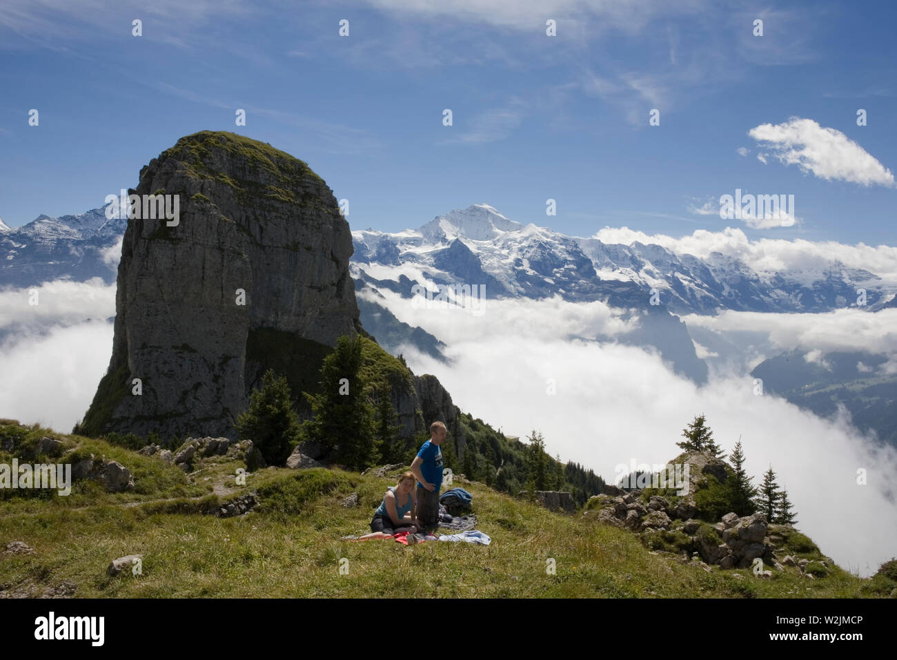 Gli escursionisti in appoggio sul Schynige Platte, con una magnifica vista della Gumihorn e vette innevate, compreso lo Jungfrau in distanza, Svizzera Foto Stock