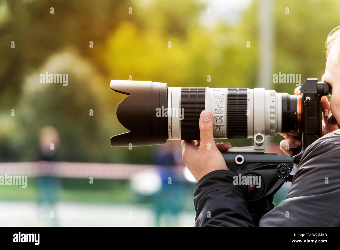 Processo di scattare fotografie all'aperto. Fotografo professionista esegue lo zoom per fare un colpo. Uomo spara con una lente moderno all'esterno. Le riprese con lente Foto Stock