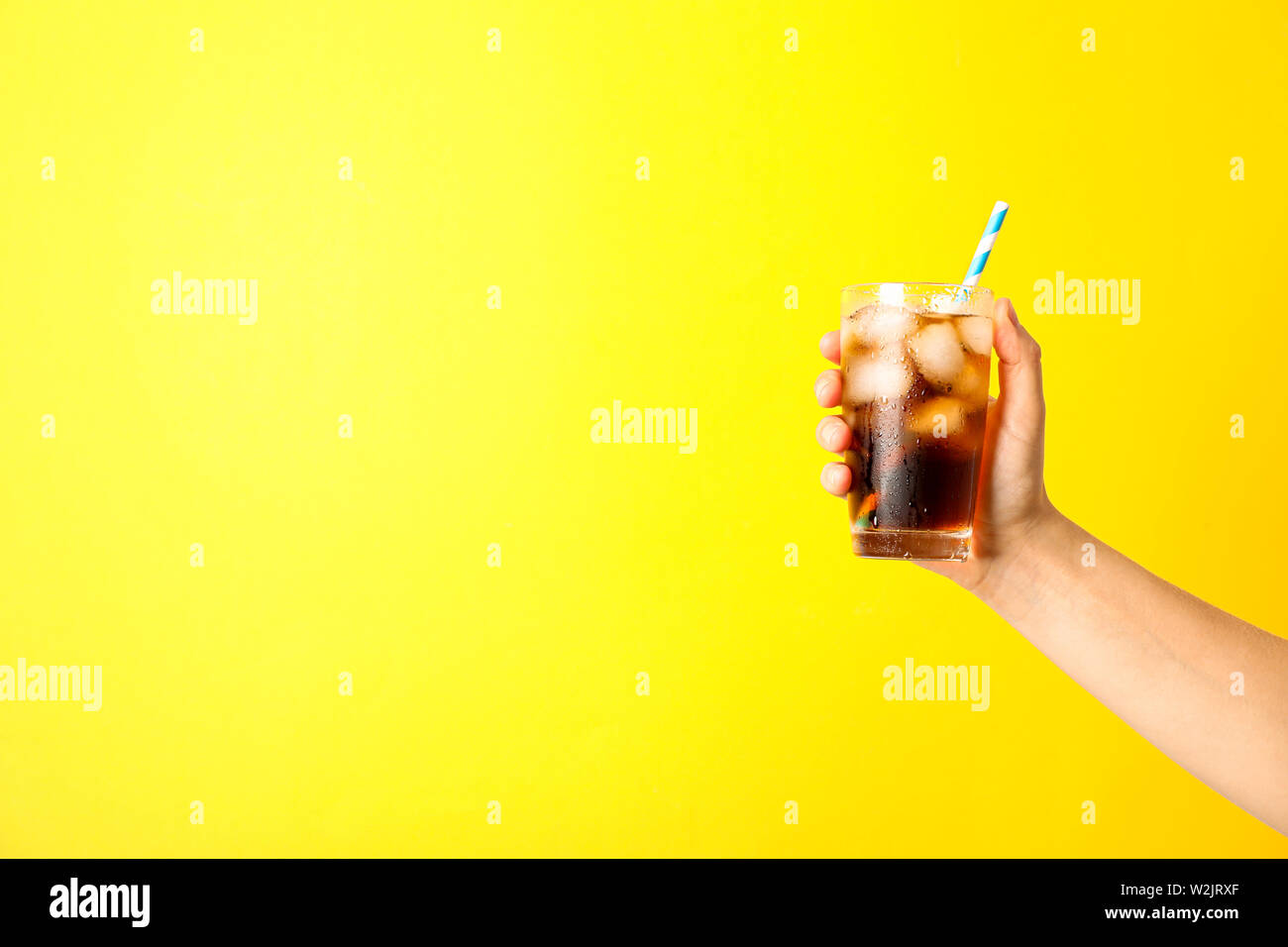 Femmina di mano in mano un bicchiere con ghiaccio di cola e del tubicino Foto Stock