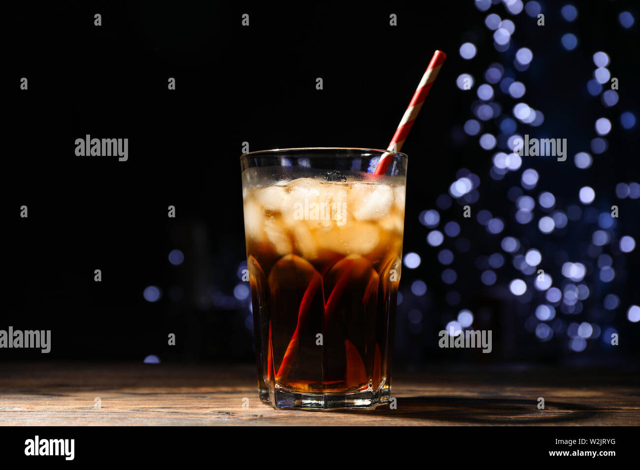 Vetro con cola, lime slice e contro dei tubuli sfocata sullo sfondo delle luci Foto Stock